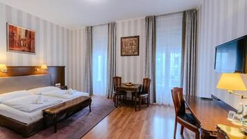A hotel room with a bed, a desk, a chair, a television, and a painting on the wall.