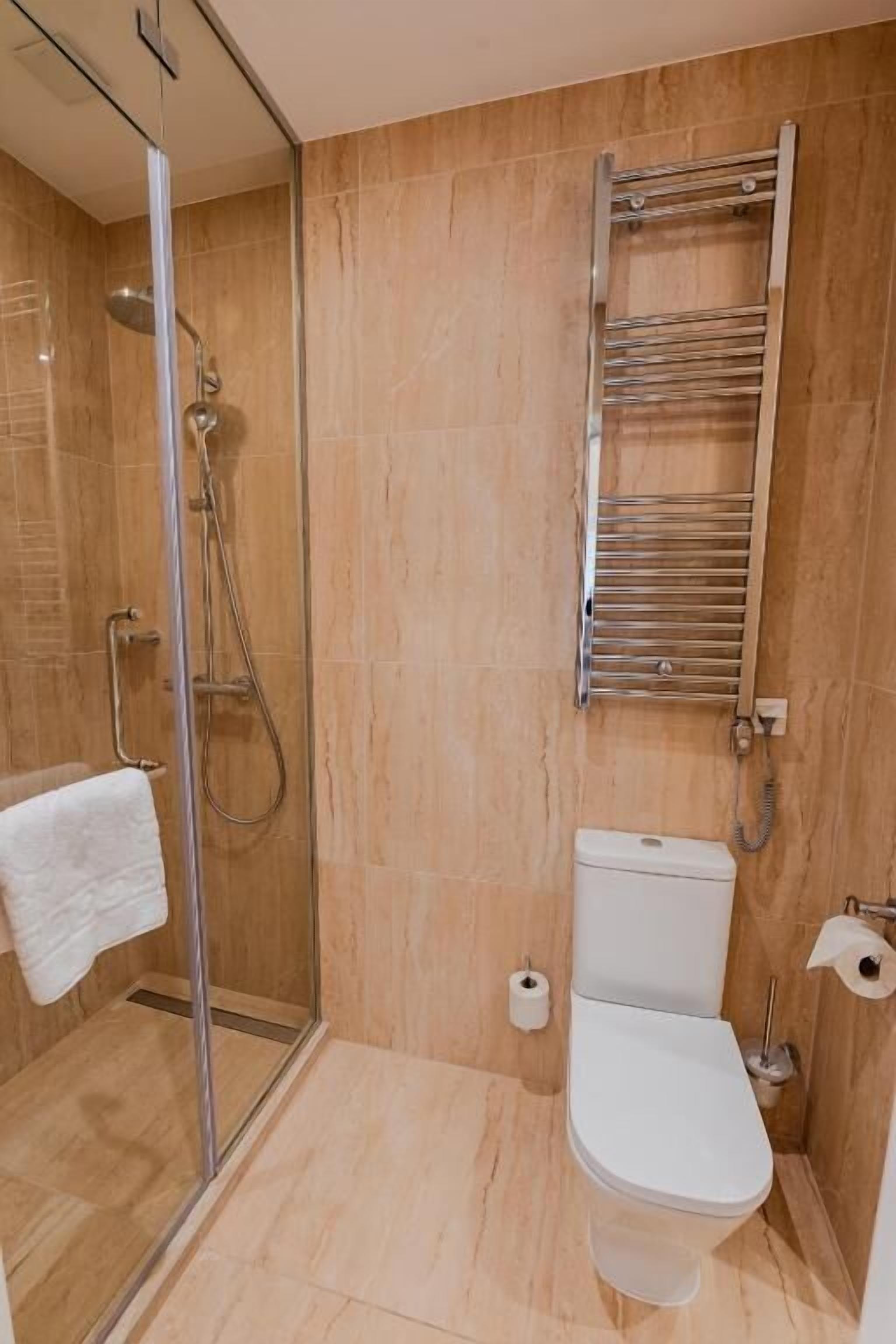 Une salle de bain avec une douche à parois de verre, des toilettes et un porte-serviettes.