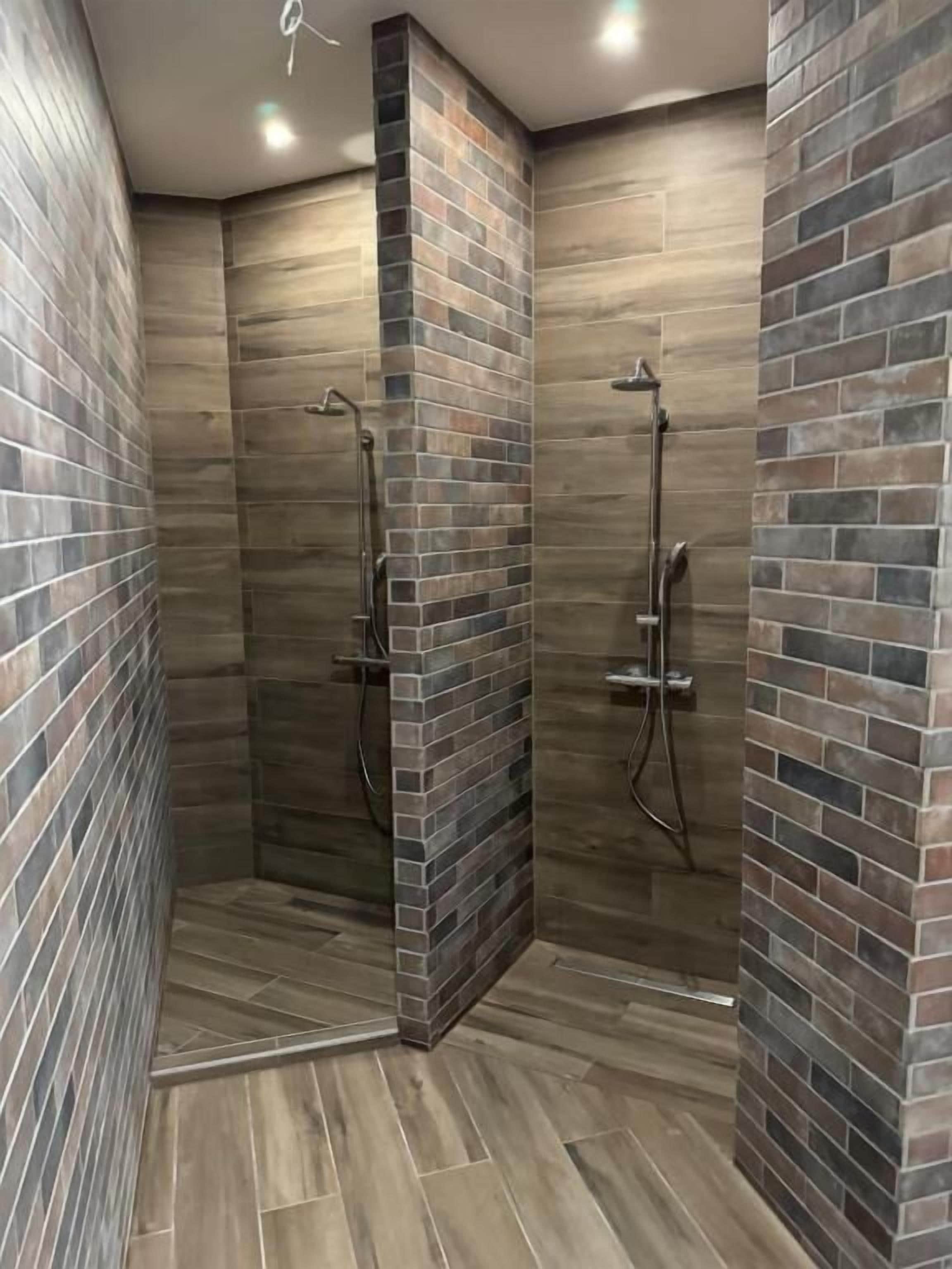 A shower area with tiled walls and a wooden floor.