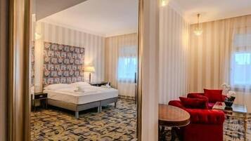 Een hotelkamer met een grote spiegel, een bed, een rode stoel, een klein tafeltje en een kamerbreed tapijt met een patroon.