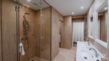 Een moderne badkamer met een douchecabine van glas, twee wasbakken en een grote spiegel.