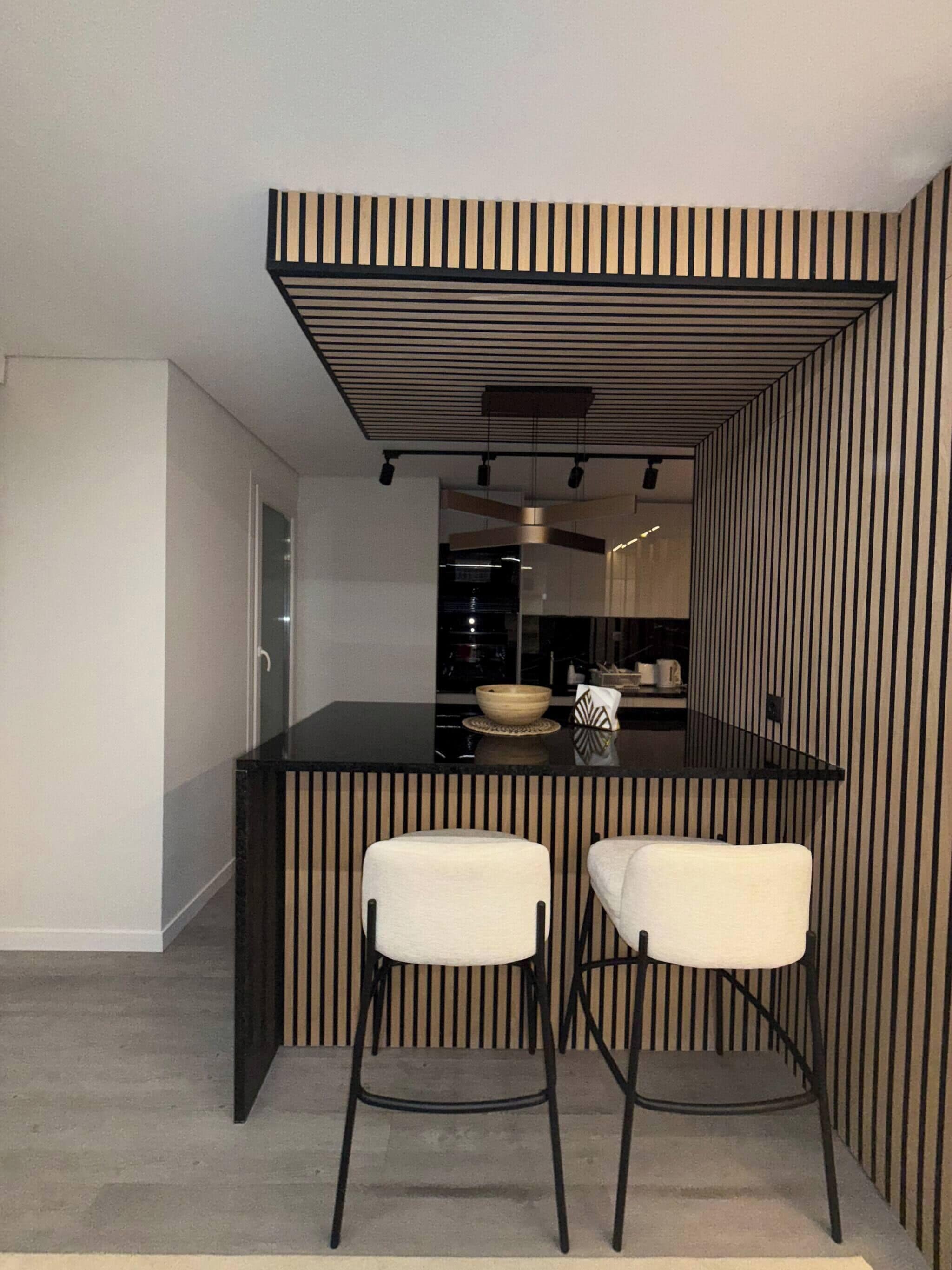 Una cocina moderna con un salpicadero a rayas blancas y negras, una isla central con taburetes y una encimera visible.