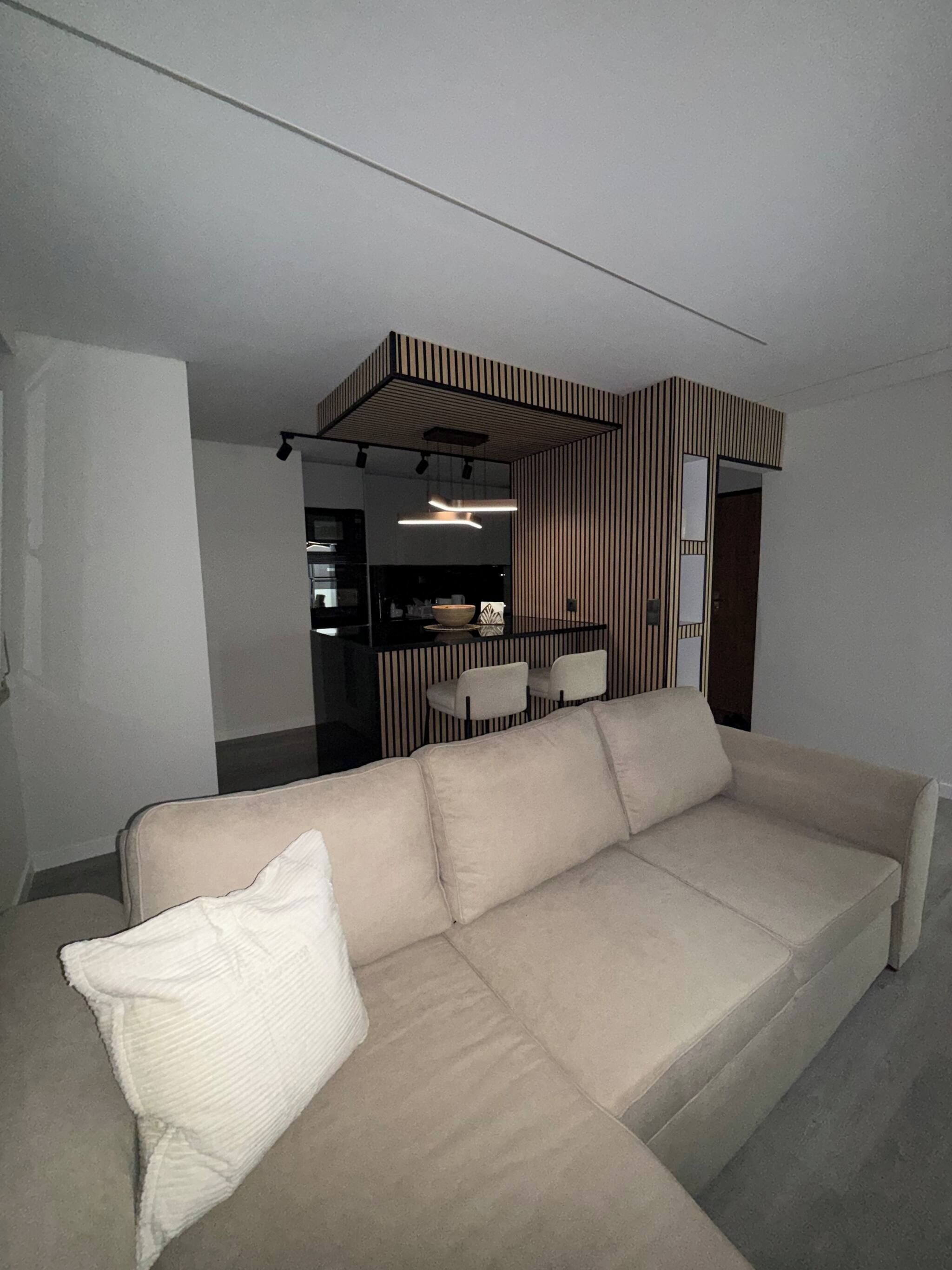 A modern living room with a sectional sofa, a dining area with chairs, and a kitchen in the background.