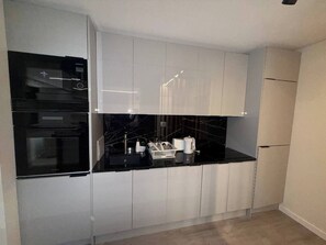 A modern kitchen with white cabinets, a black countertop, and a built-in oven. - Luxury 3BR Apartment 2 Baths Near Lisbon & Sintra (Sintra)