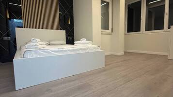 Un dormitorio moderno con una cama grande, un cabecero de madera y una ventana con persianas.