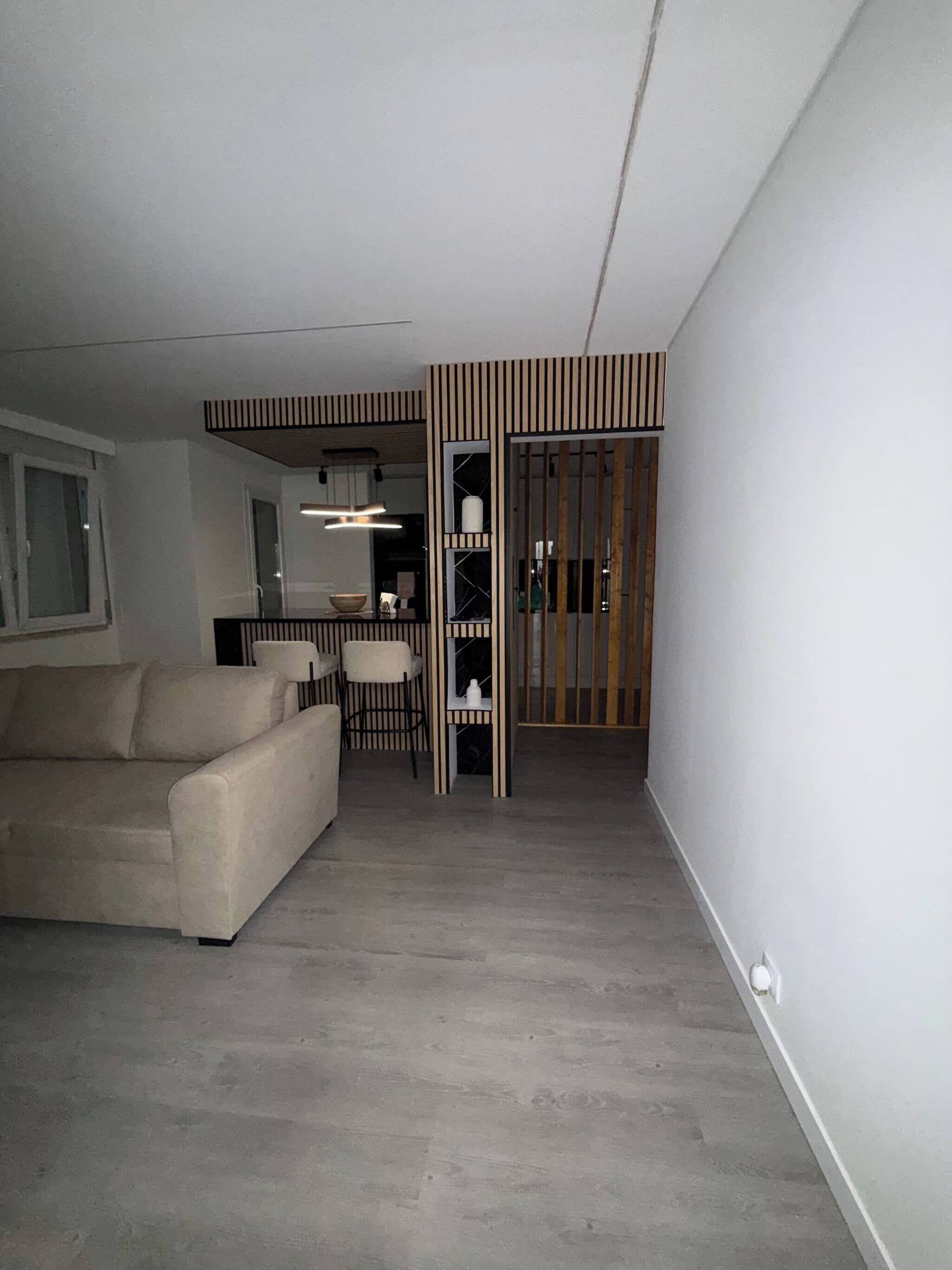 Una sala moderna con un sofá, una mesa de comedor con sillas y una cocina con mostrador y armarios.