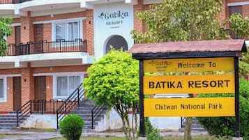Een bordje voor Batika Resort, met een trap die naar een gebouw met een bakstenen gevel leidt.