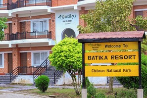 A sign for Batika Resort with a staircase leading to a building with a brick facade. - Batika Resort Sauraha (Sauraha)