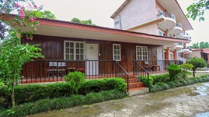 Un edificio de dos pisos con fachada de madera, un balcón y un sendero empedrado.