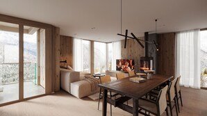 Ein geräumiger Wohnbereich mit großem Fenster, einer Couch, einem Esstisch mit Stühlen und einem Kamin.