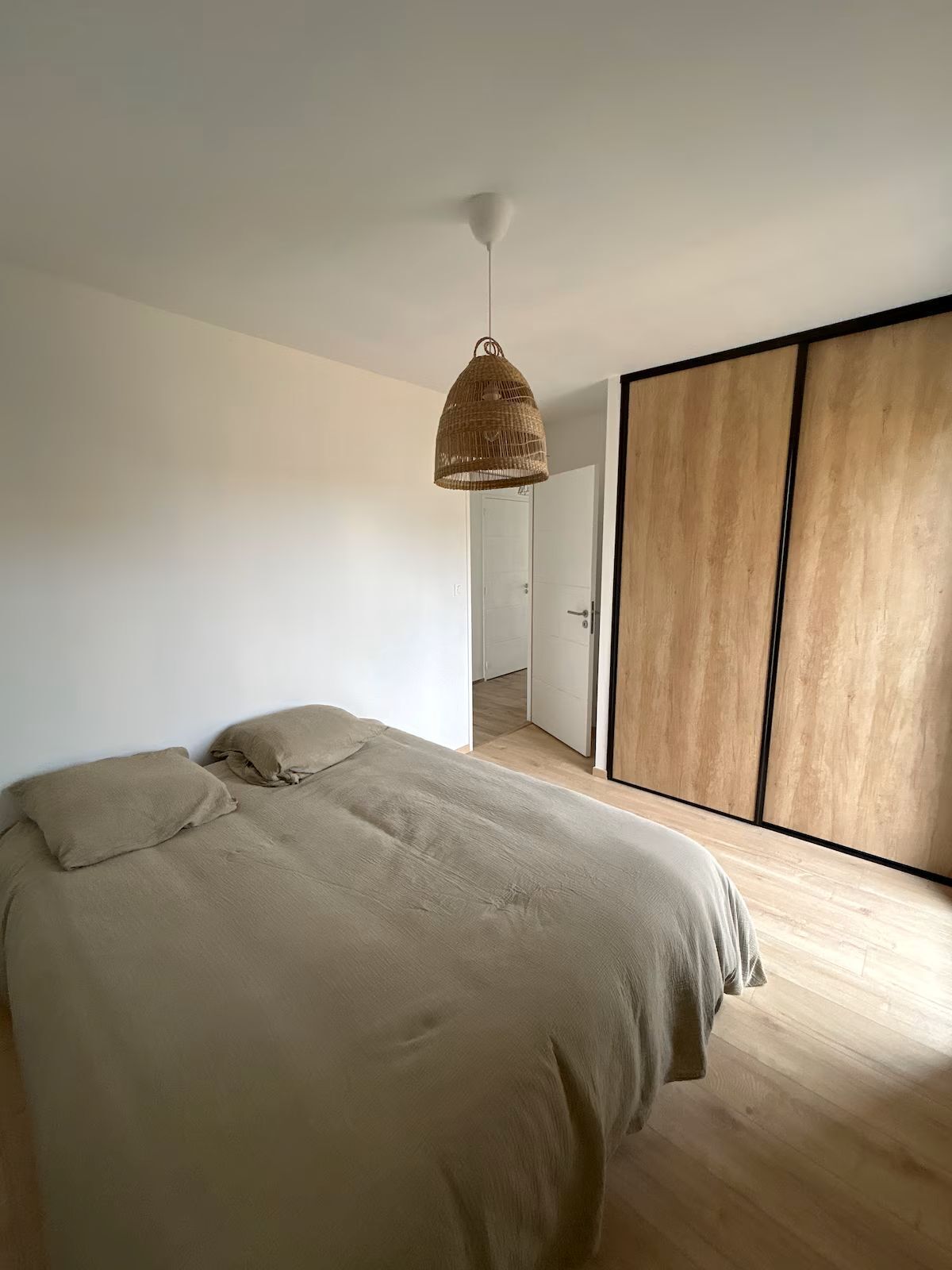 Une chambre à coucher avec un lit, un luminaire suspendu et une porte coulissante.