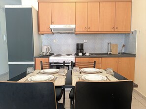 Een keuken met houten kastjes, een fornuis, een koelkast en een eettafel gedekt voor twee personen.
