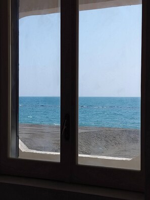 Ein Fenster mit Blick auf das Meer und einen Sandstrand.