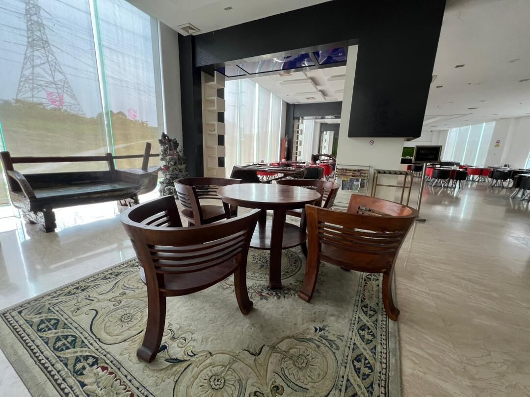 A spacious room with a large window, a round table with chairs, and a patterned rug.