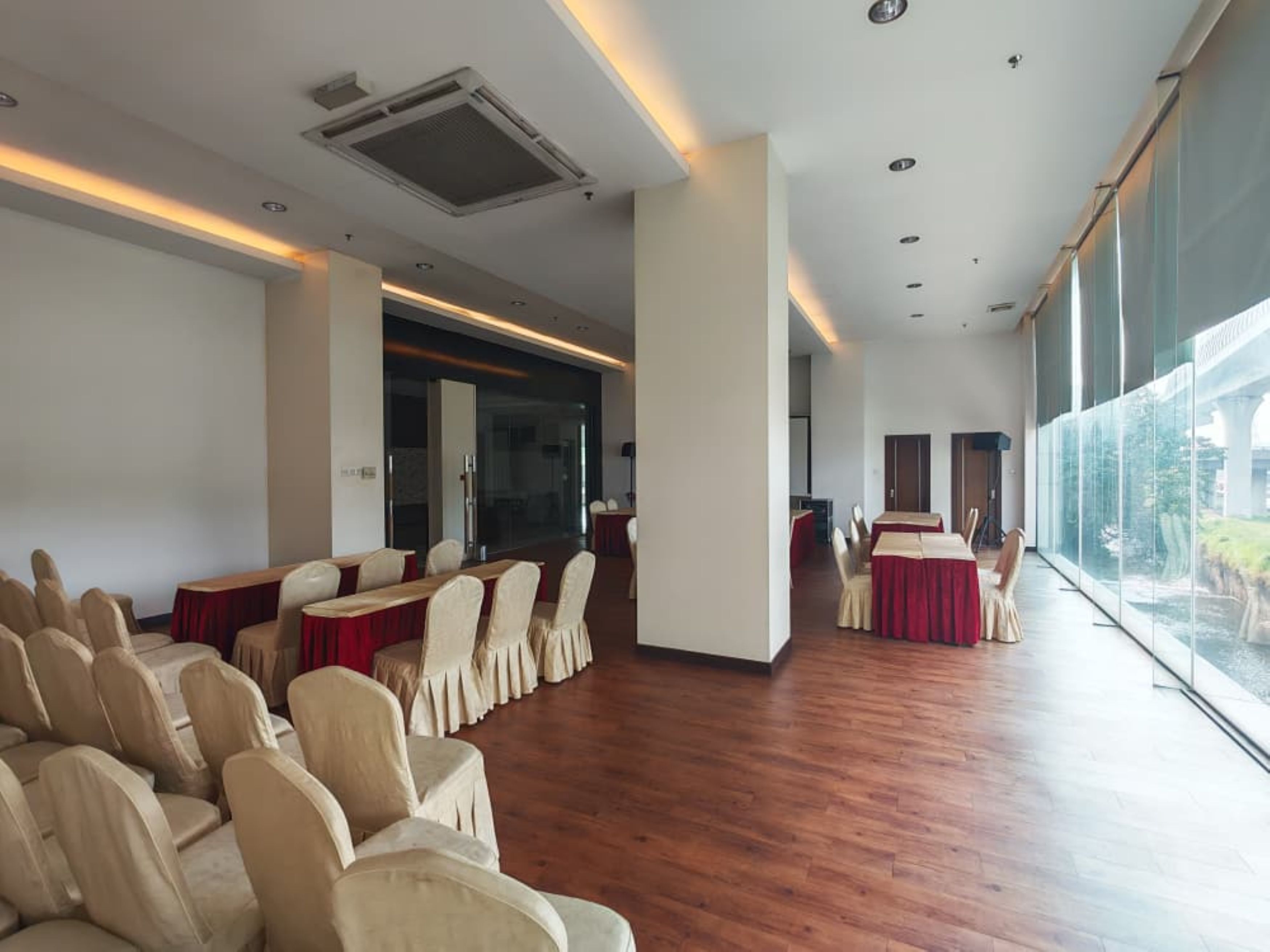 A conference room with rows of chairs and tables, large windows, and a modern ceiling design.