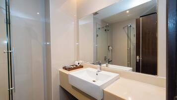 Un bagno moderno con box doccia in vetro, lavandino bianco e uno specchio grande.