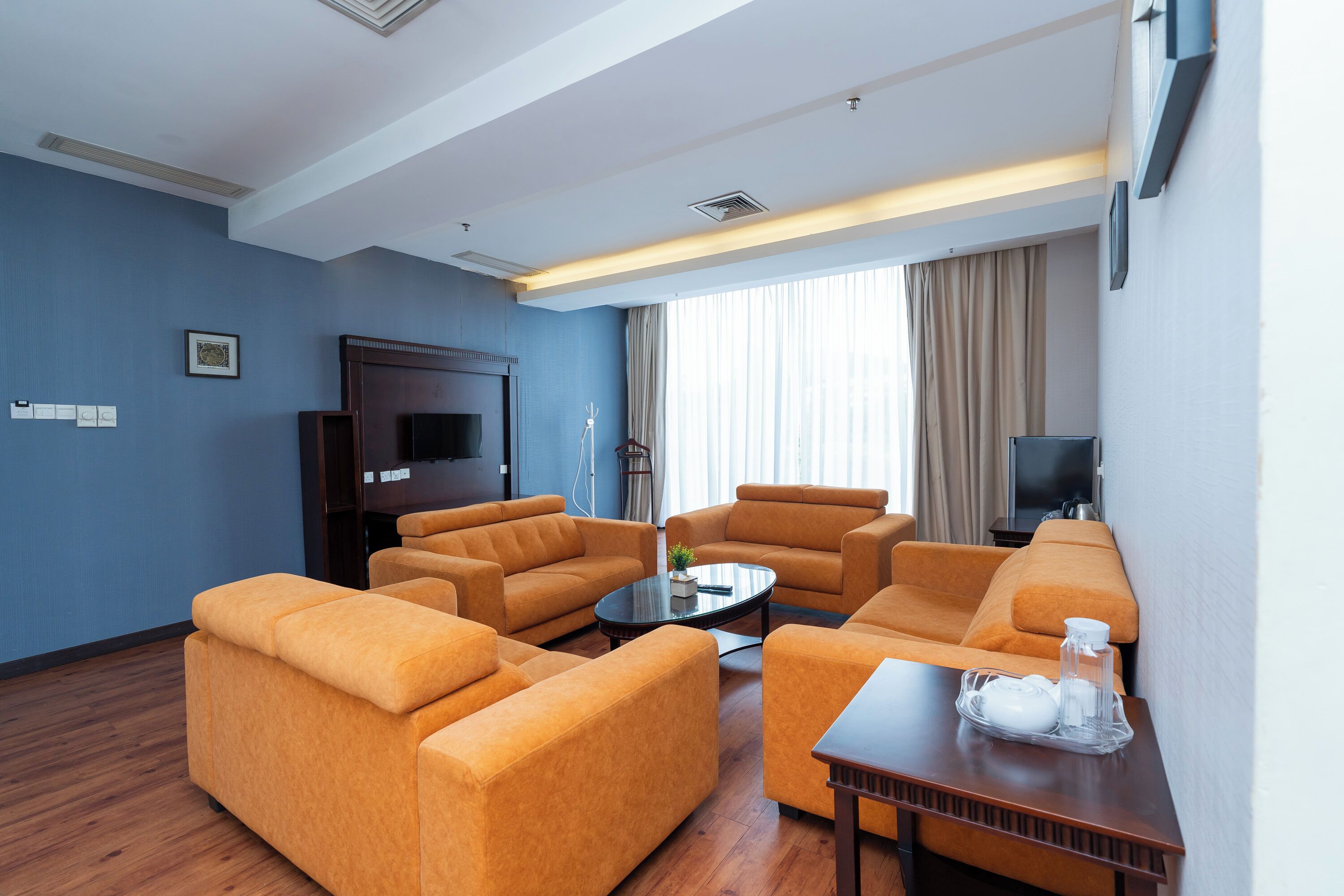 A modern living room with a sofa set, a coffee table, and a flat-screen TV mounted on the wall.