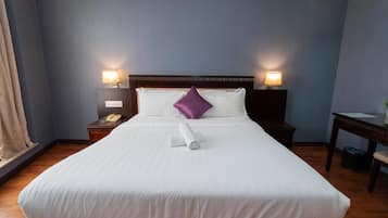 A hotel room with a large bed, two bedside lamps, a wooden nightstand, and a small table with a lamp.