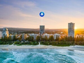A coastal cityscape with high-rise buildings, a beach, and a clear sky. - Burleigh Beach Views | 2BR, Pool, Gym & Parking (Burleigh Heads)