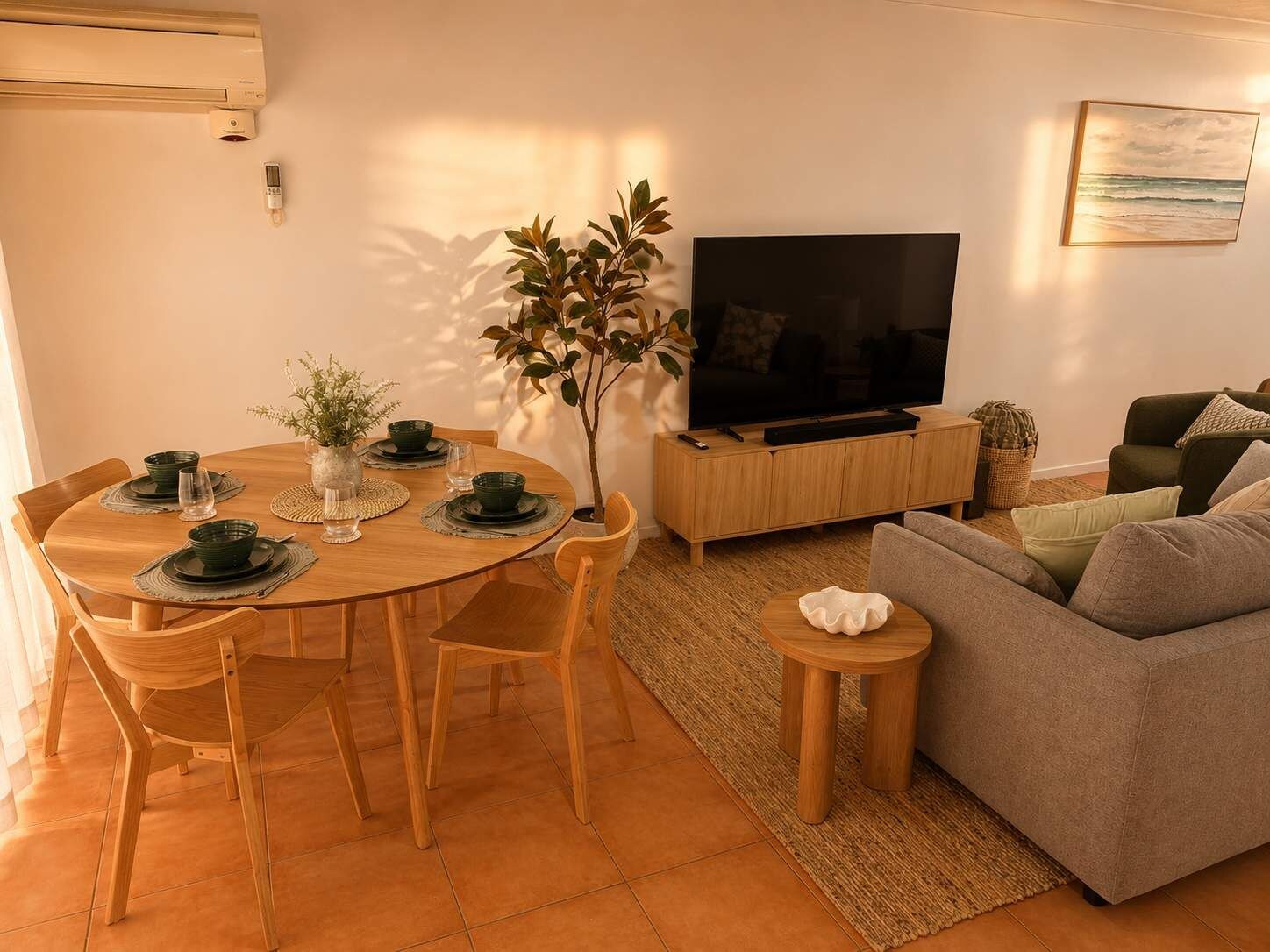 Een eetgedeelte met een ronde tafel, stoelen en een televisie op de achtergrond.