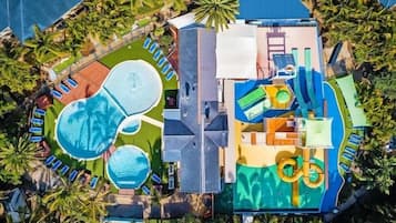An aerial view of a resort with multiple swimming pools, a water park, and a large building structure.