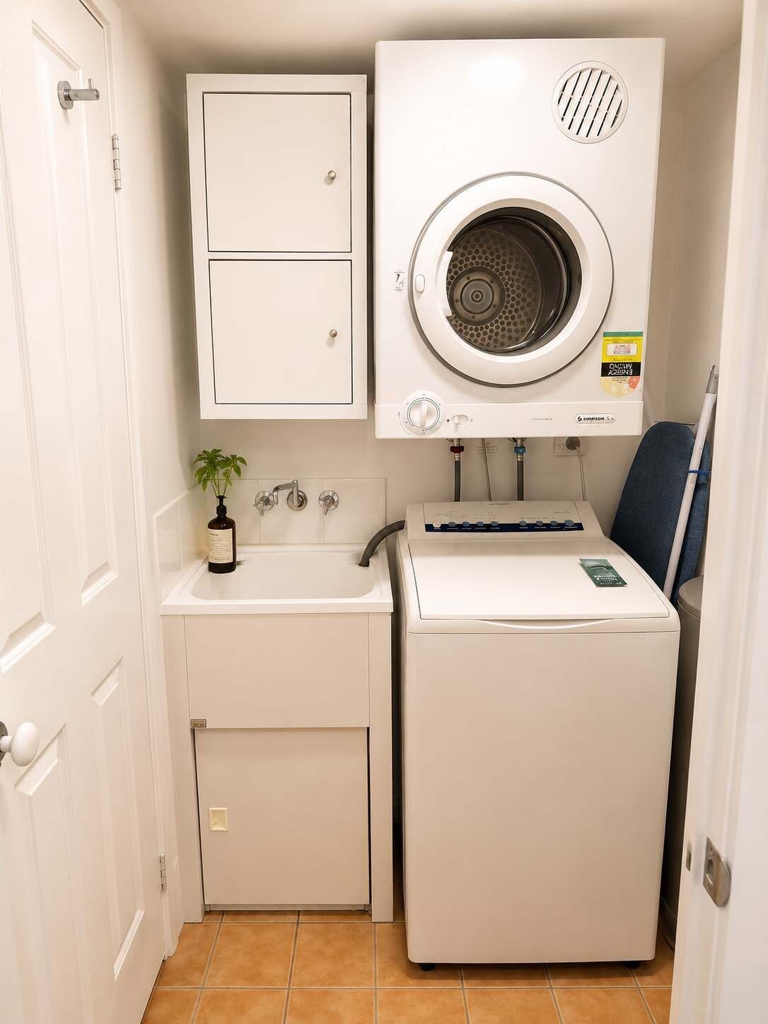 A compact laundry room with a washing machine, a small sink, and a cabinet.