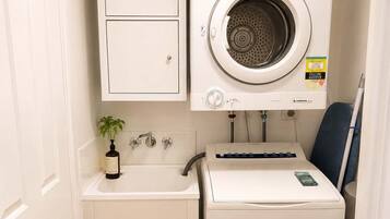 A compact laundry room with a washing machine, a small sink, and a cabinet.