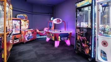 A room with arcade games, including claw machines and a racing game.
