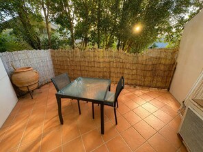 Eine Terrassengruppe mit Tisch und Stühlen, umgeben von einem Bambuszaun und Bäumen.