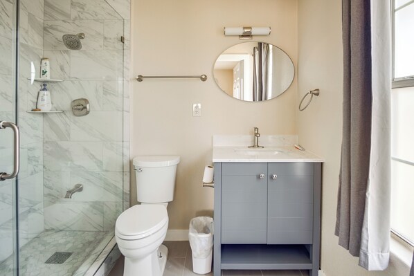 Un baño con inodoro, ducha, lavabo y espejo.