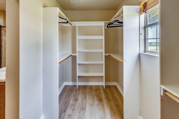 A walk-in closet with wooden flooring and white shelving units.
