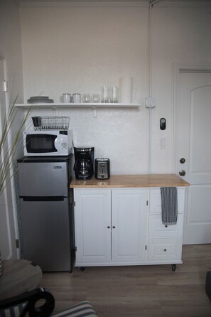 A compact kitchen with a refrigerator, microwave, coffee maker, and toaster.