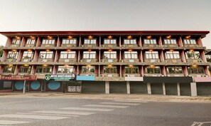 A multi-story building with balconies, air conditioning units, and signage for a restaurant and an auditorium.