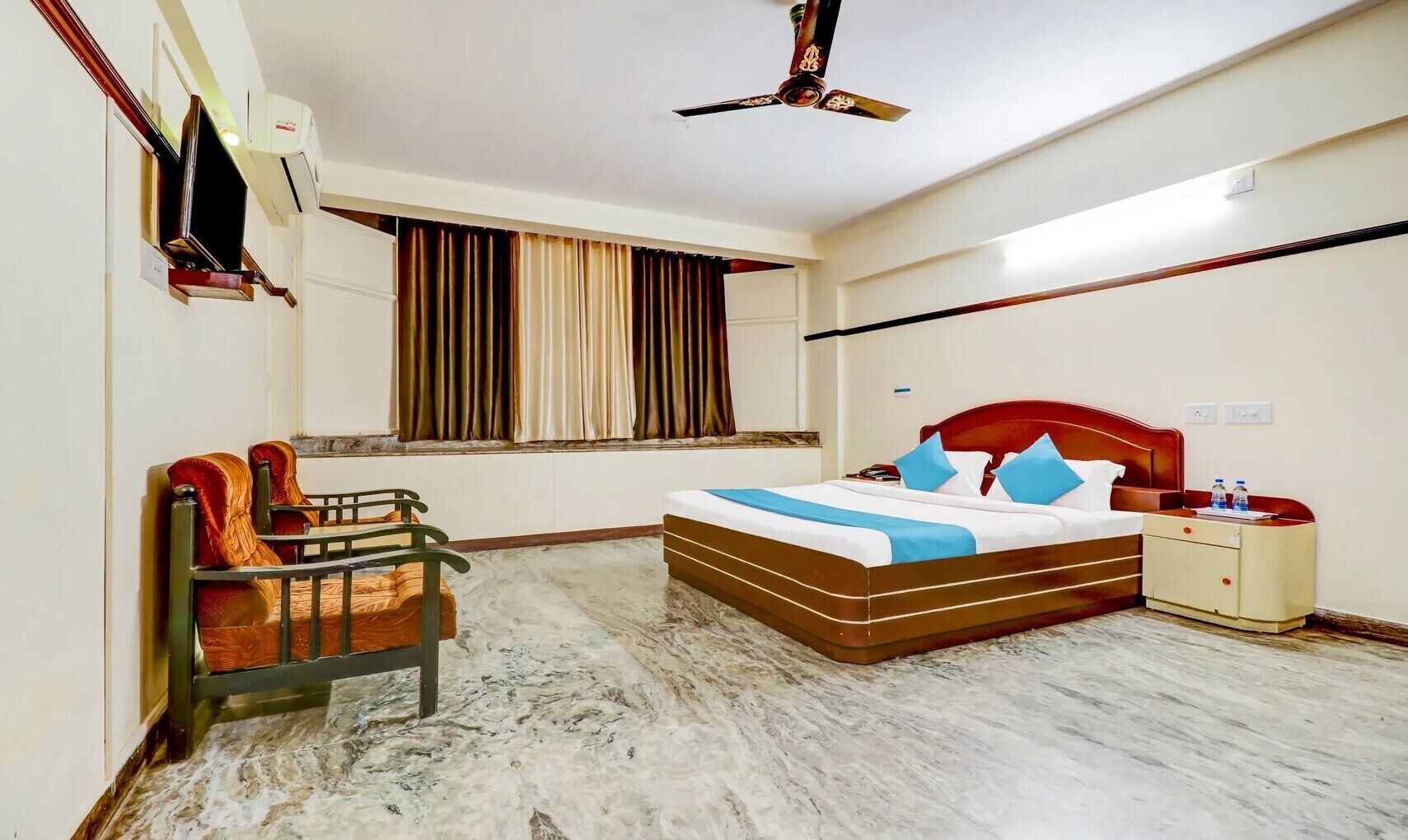 A hotel room with a bed, bedside table, and a desk with a chair.