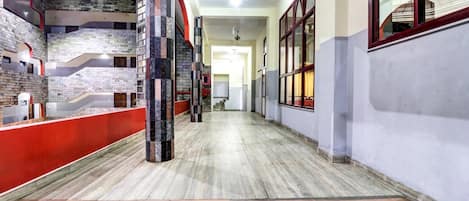 A corridor with a marble floor, red and white walls, and a staircase on the left.