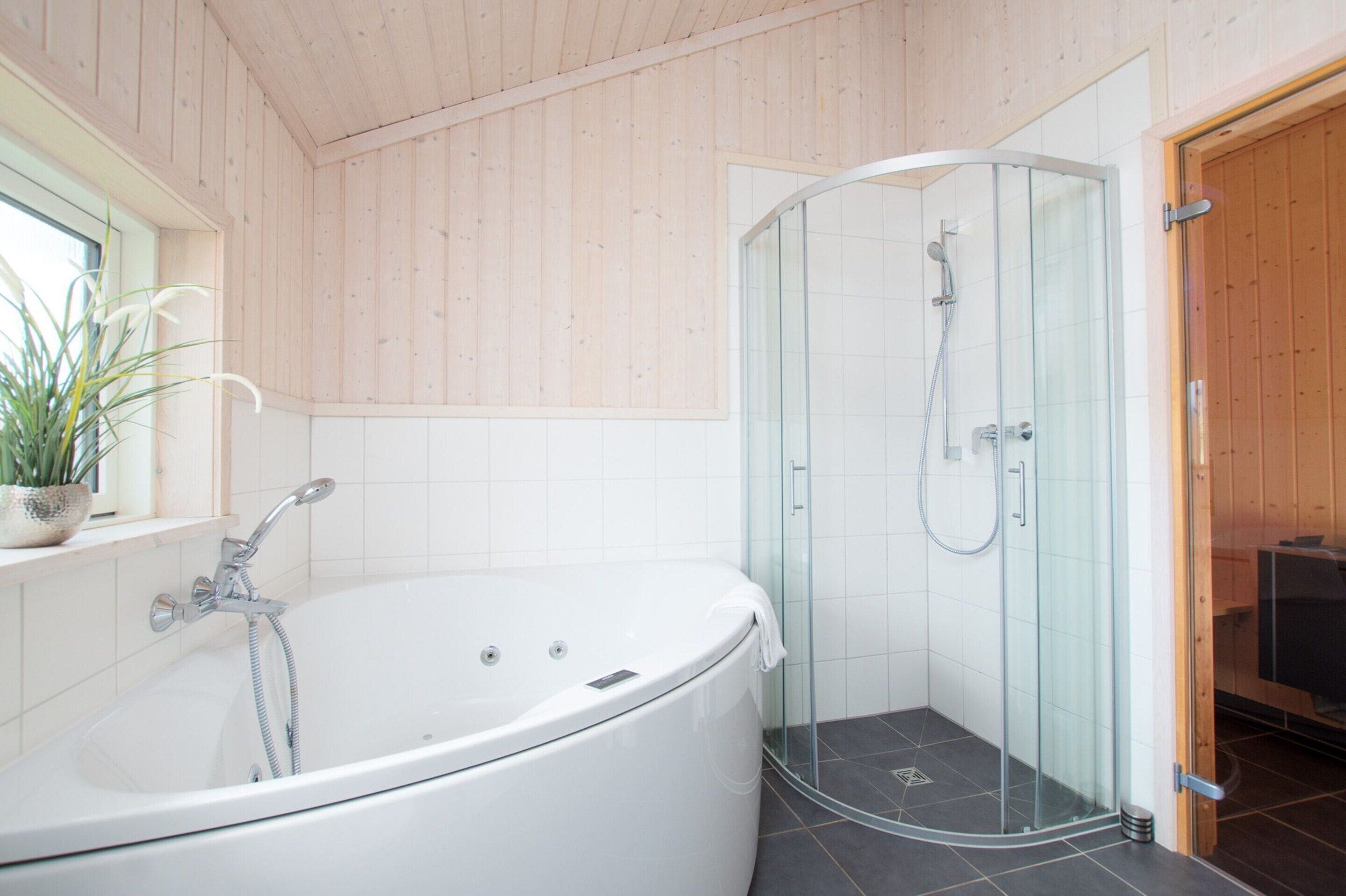 A modern bathroom with a freestanding bathtub, a glass-enclosed shower, and a wooden ceiling.
