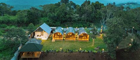 Un resort apartado con varias cabañas en los árboles rodeado de exuberante vegetación y vistas a montañas distantes.