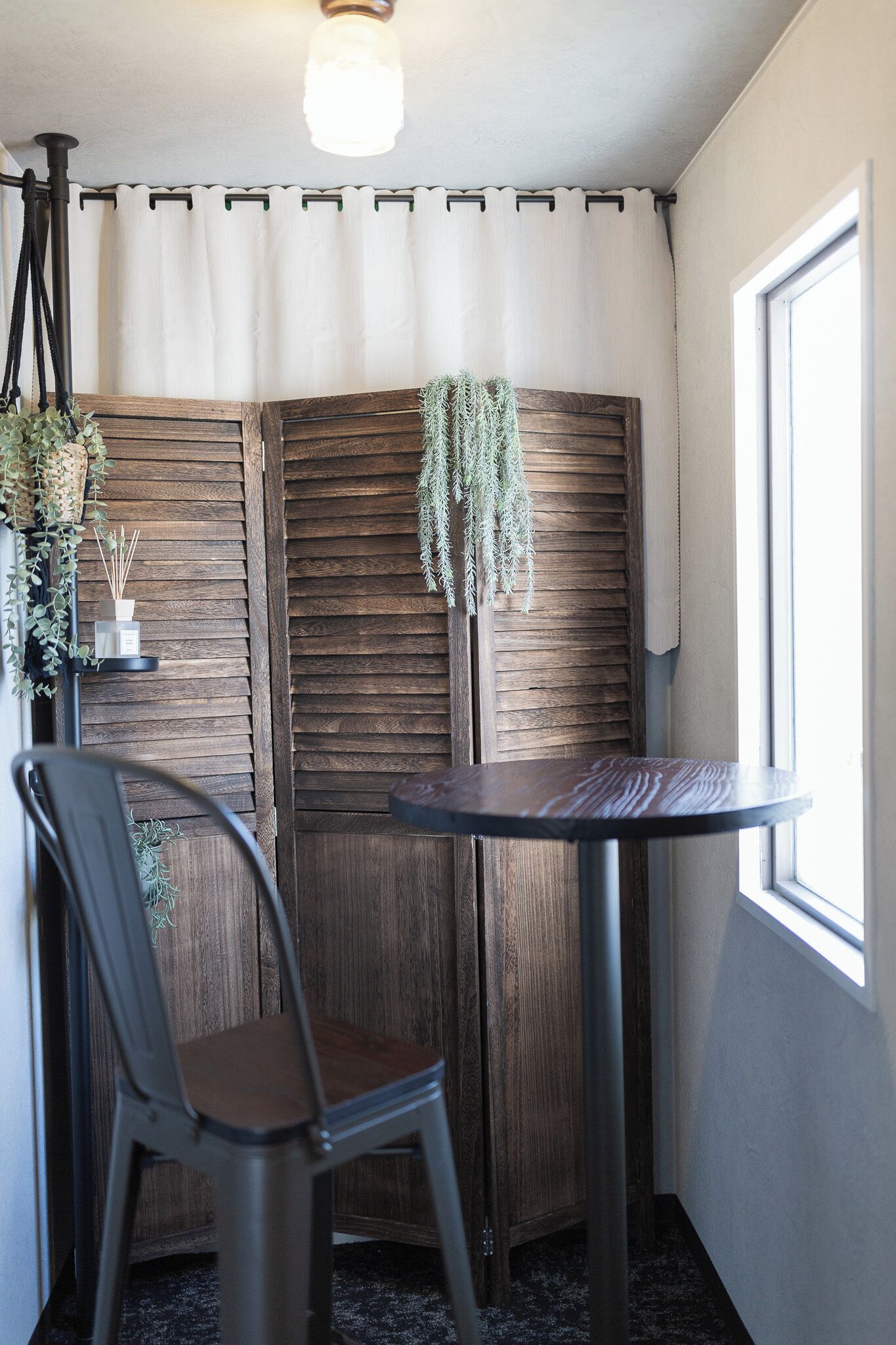 A corner room with a wooden partition, a round table, a chair, and a window.