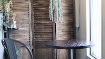 A corner room with a wooden partition, a round table, a chair, and a window.