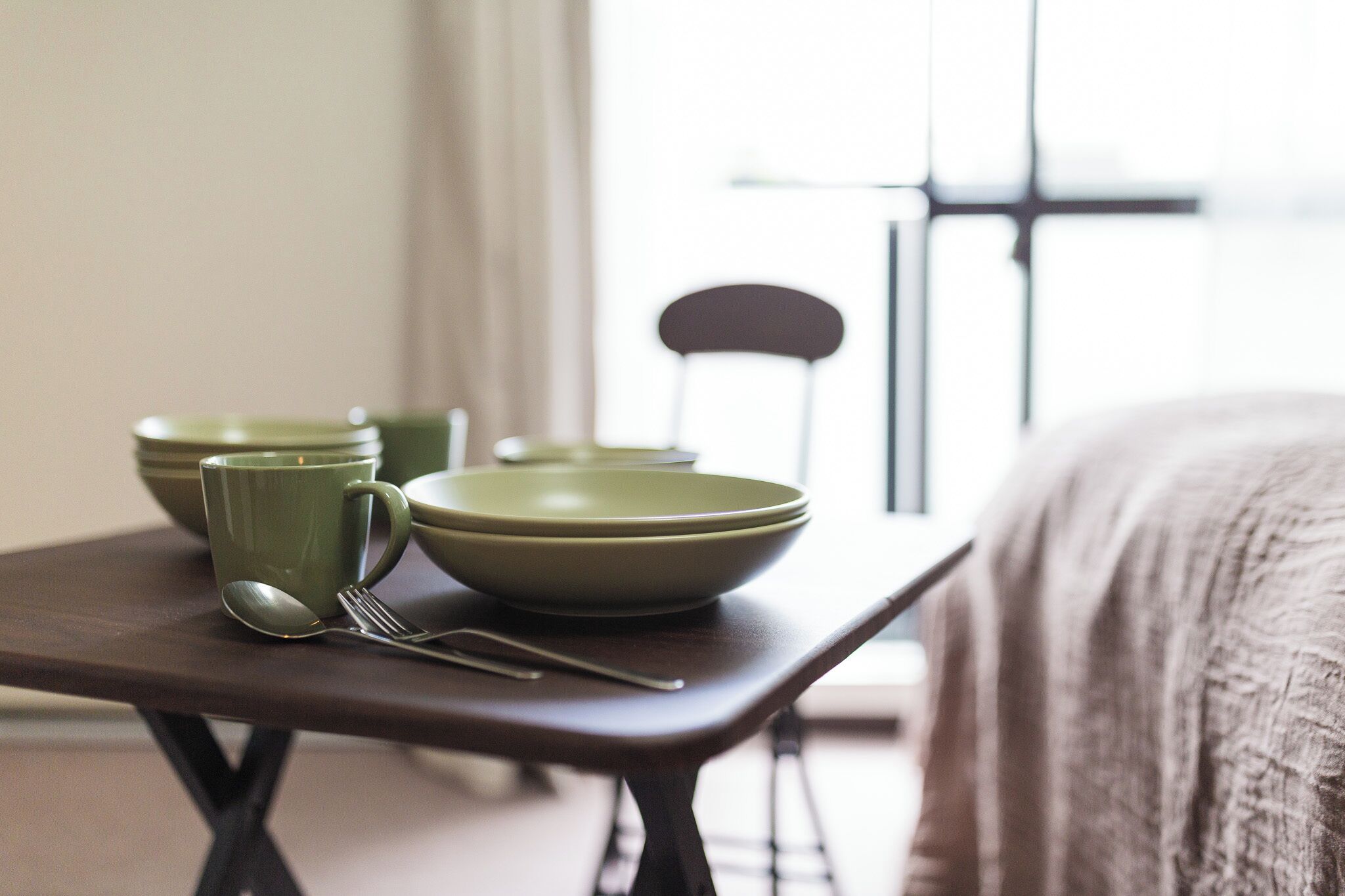 Una mesa de comedor con cuencos verdes, una cuchara y un tenedor.