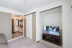 A hotel room with a television, a sofa, a sliding door leading to a kitchenette, and a carpeted floor. - b&Dotonbori 2 (Chuo Ward)