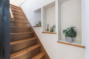 Una escalera de madera con estantes empotrados que sostienen plantas y objetos decorativos.