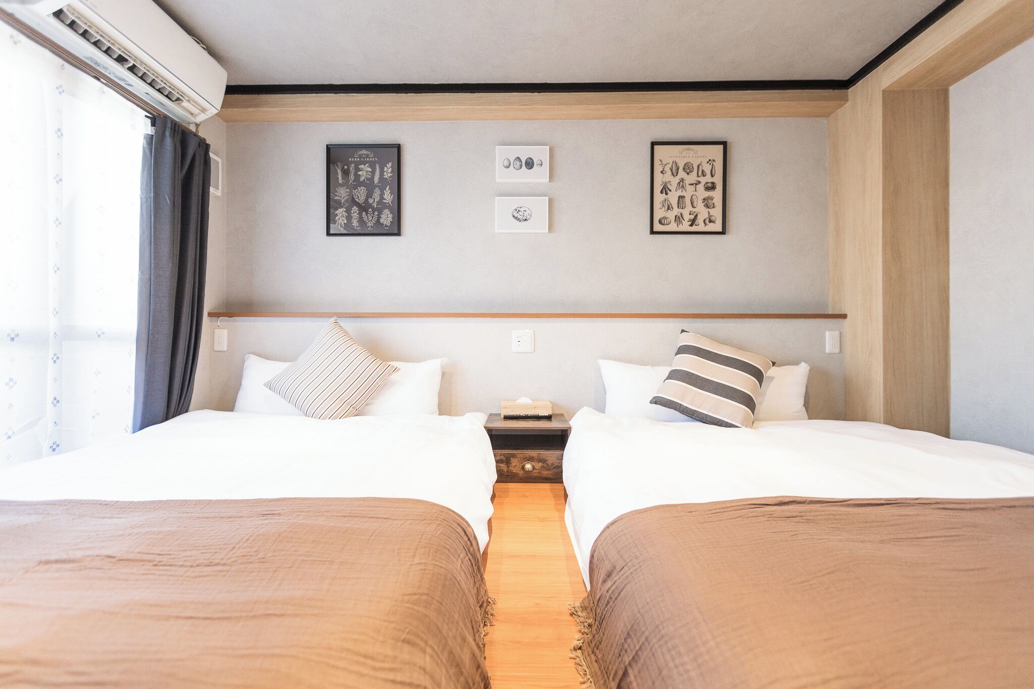 A hotel room with two beds, a nightstand, and wall art.