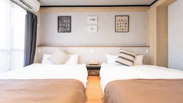 A hotel room with two beds, a nightstand, and wall art.