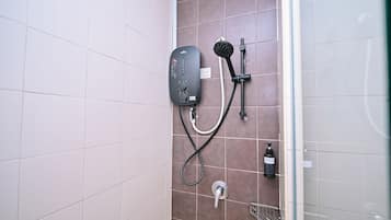A bathroom with a shower unit, a handheld showerhead, a bottle of shampoo, and a towel rack.