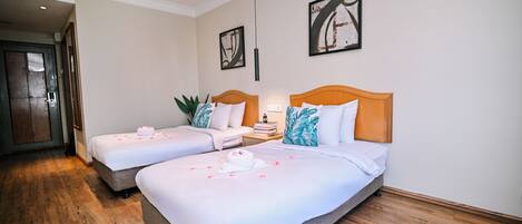 A hotel room with two beds, a wooden floor, and artwork on the walls.