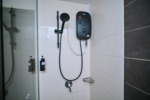 A bathroom with a glass shower enclosure, a handheld showerhead, a wall-mounted control panel, and a bottle of shampoo. - Kingston Hotel 11 @ PWTC, KL (Kuala Lumpur)