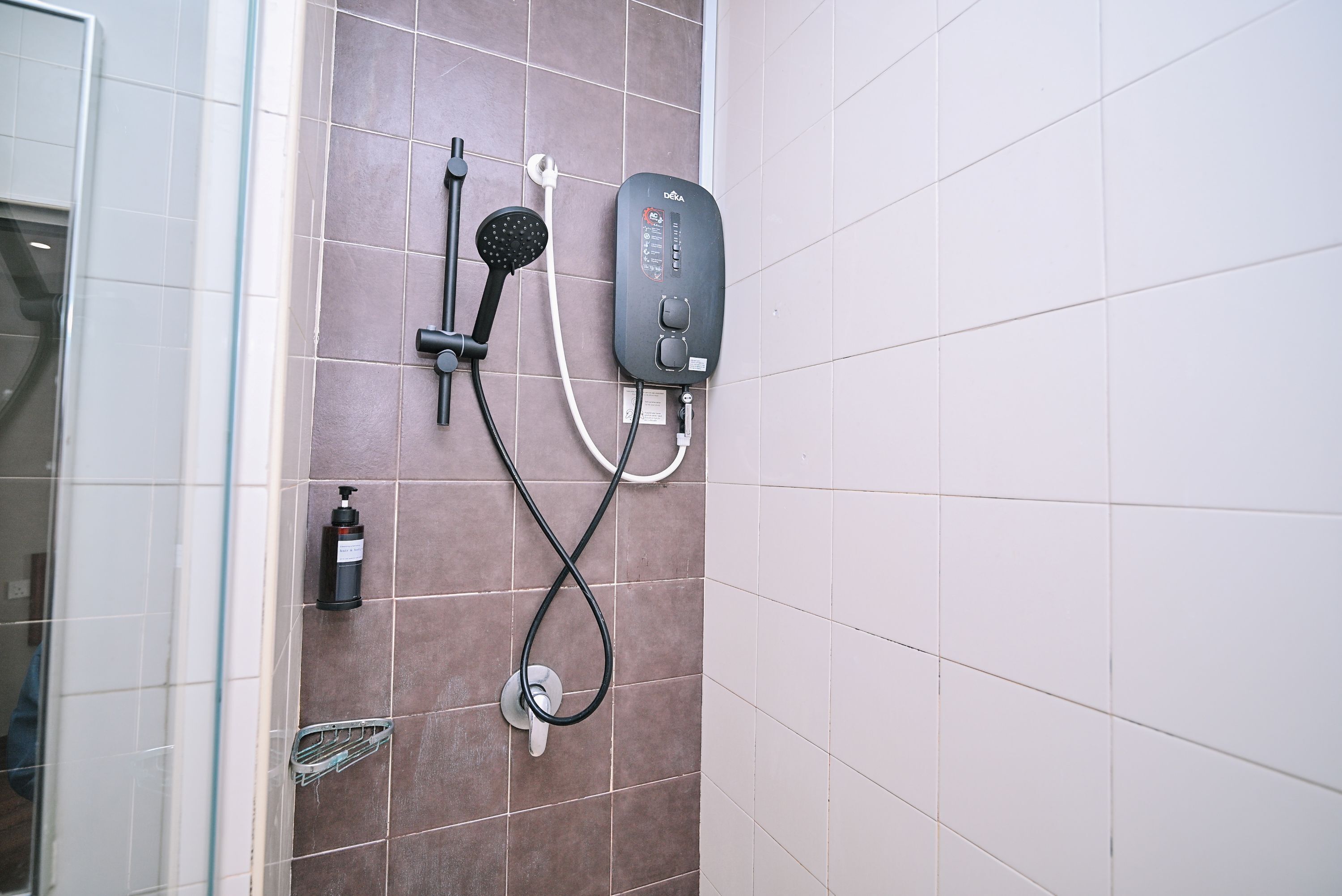 A shower with a handheld showerhead and a wall-mounted control panel.
