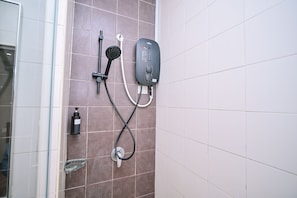 Ducha con cabezal de ducha de mano y panel de control en la pared.