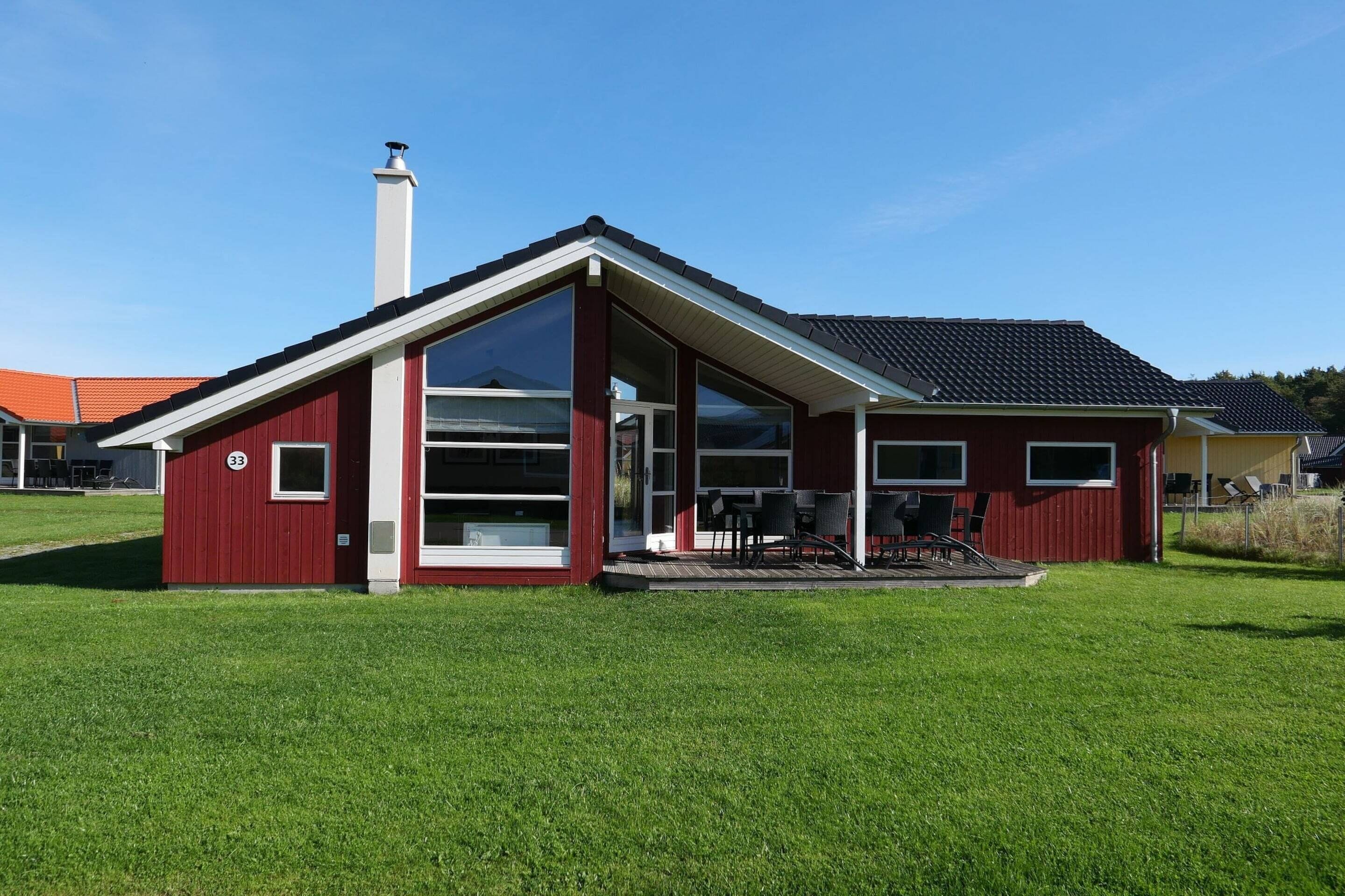 A red building with a large glass window, a chimney, and a covered outdoor seating area.